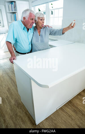 Playful senior couple making faces while taking selfie Stock Photo
