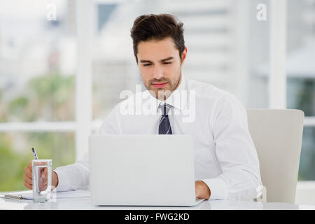Businessman using laptop and taking notes Stock Photo