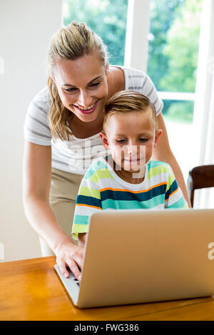 Smiling mother and son using laptop at home Stock Photo