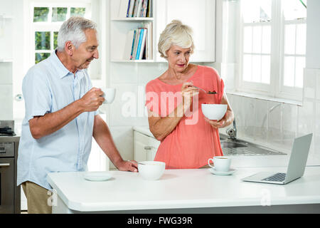 Senior couple having breakfast while using laptop Stock Photo