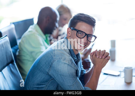 Young man sitting at his desk smiling at camera Stock Photo