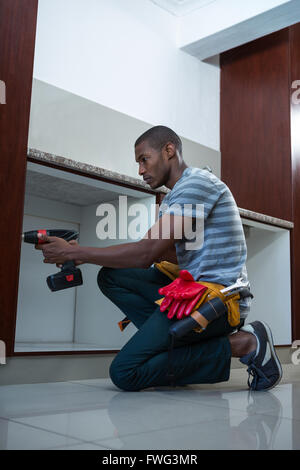 Manual worker drilling a hole in kitchen Stock Photo