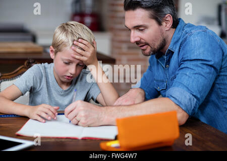 Father helping son with his homework in kitchen Stock Photo