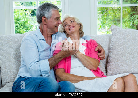 Loving senior couple looking at each other in living room Stock Photo