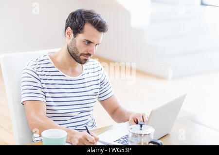 Man writing note using laptop Stock Photo