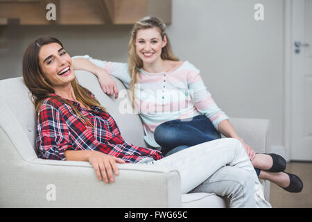 Portrait of two beautiful women sitting on sofa Stock Photo