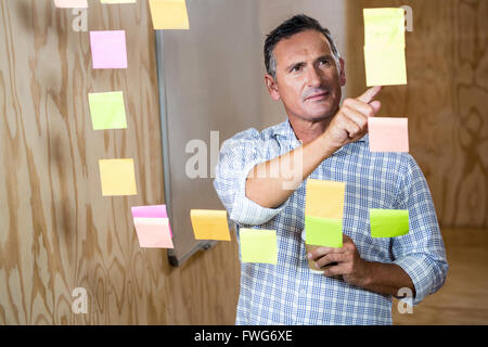Thoughtful man reading at sticky notes while having coffee Stock Photo