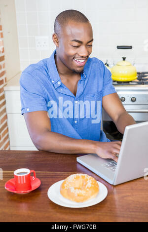 Young man having breakfast and using laptop Stock Photo