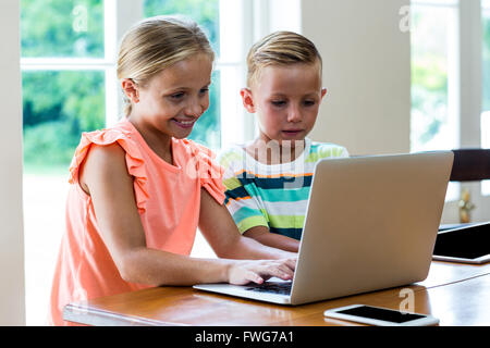 Siblings using laptop while sitting at home Stock Photo