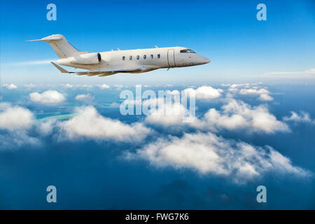 Luxury private jet plane flying above clouds in day light Stock Photo