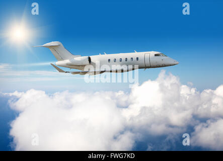 Luxury private jet plane flying above clouds in day light Stock Photo