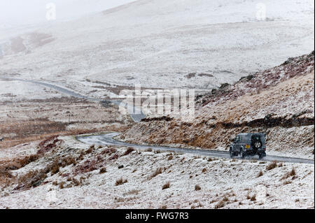 A four wheel drive vehicle negotiates a road through a wintry landscape in the Elan Valley area in Powys, Wales, UK. Stock Photo