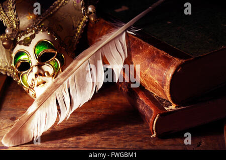 Art concept. Vintage still life with old books near Venetian mask and quill pen Stock Photo
