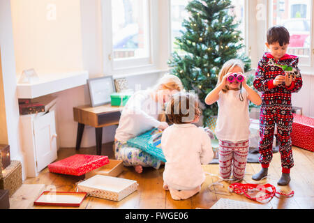A mother and three children on Christmas morning opening presents. Stock Photo