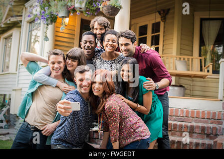 A group of friends posing on the steps of a house porch, taking a group selfy. Stock Photo