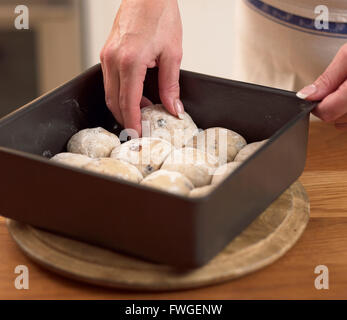 Placing buns in a baking tray ready to place in the oven. Stock Photo