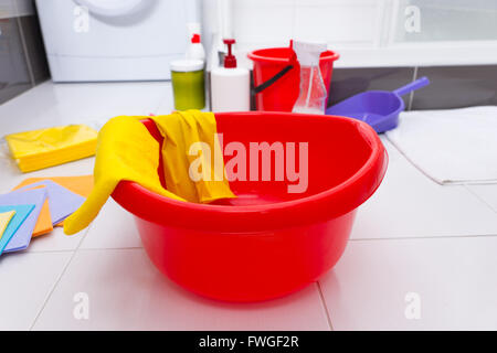 Colorful collection of household cleaning products with a red basin, yellow gloves and cloths, assorted containers of chemicals Stock Photo