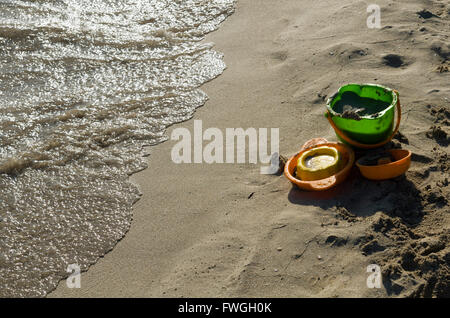 Beach toys left on the shore near the undertow Stock Photo