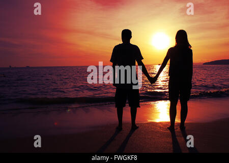 Full Length Of Silhouette Couple Standing On Beach Against Orange Sky