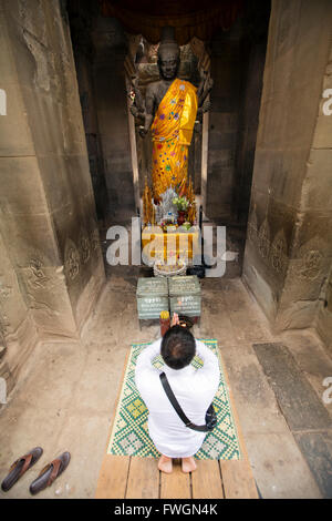 A man praying in front of a statue of Buddha, Angkor Wat, Siem Reap, Cambodia, Southeast Asia Stock Photo
