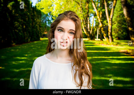 A beautiful young girl poses for a fashion style portrait outdoors at a park with natural lighting. Stock Photo