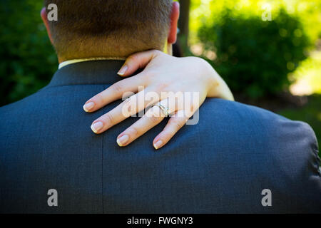 The bride puts her hand over the shoulder of the groom while dancing to create this image that focuses on her wedding band ring. Stock Photo