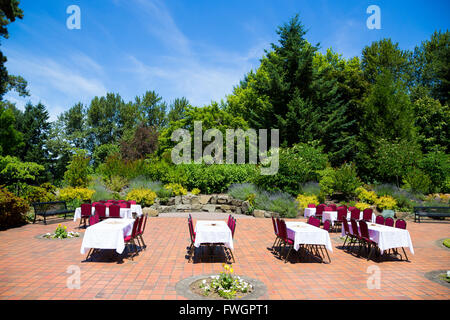Some tables and chairs are set up ready for a wedding reception as soon the ceremony is finished outdoors in Oregon at a park. T Stock Photo