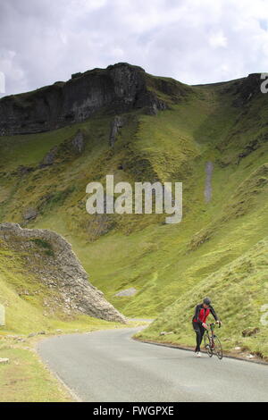 A cyclist pushes his bike up Winnats Pass, a steep limestone cleft in Castleton,  Peak District, Derbyshire England UK Stock Photo