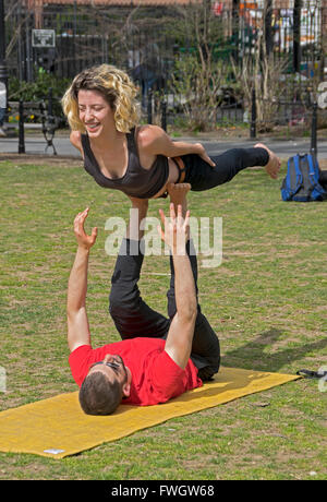 An athletic fit man and woman do acro yoga exercises in Washington Square Park in New York City Stock Photo