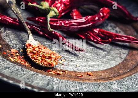 Chili. Chili peppers. Several dried chilli peppers and crushed peppers on an old spoon spilled around. Mexican ingredients - cui Stock Photo