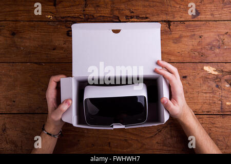 Unrecognizable man unpacking virtual reality goggles, wooden tab Stock Photo