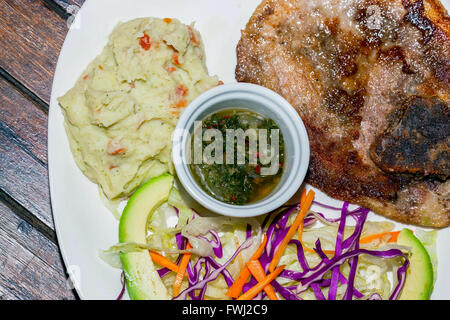 Close Up Of A Plate With Grilled Pork And Mashed Potatoes, Honey Mustard And Chimichurri Sauce Stock Photo