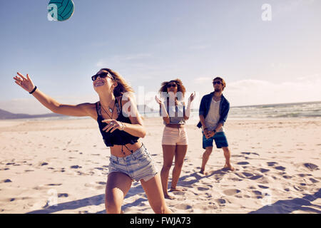 Group of friends playing volleyball on the sandy beach and having fun. Young people on summer holidays playing with ball on the Stock Photo