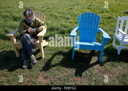 Woman using smart phone in Adirondack chair Stock Photo