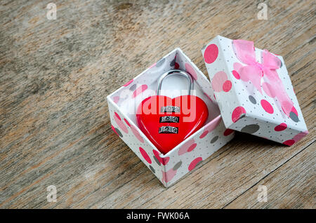 Red padlock  heart shape in gift box on wooden background. Stock Photo