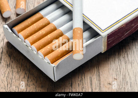 Tobacco cigarette in the box of matches on wooden background. Stock Photo