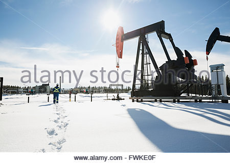 Worker walking toward drilling rigs in snow