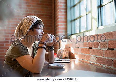 Pensive young woman drinking coffee in coffee shop