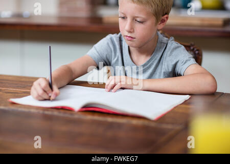 Boy doing homework in kitchen Stock Photo