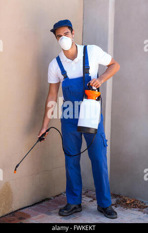 Portrait of worker spraying chemical on wall Stock Photo