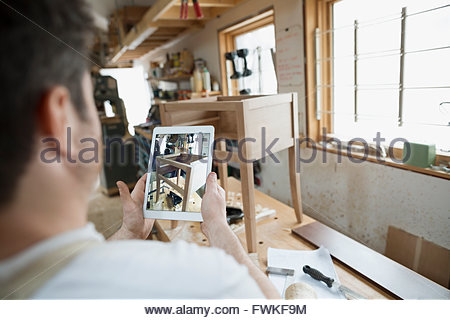 Carpenter photographing furniture with digital tablet in workshop