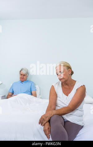 Sad senior couple sitting on bed Stock Photo