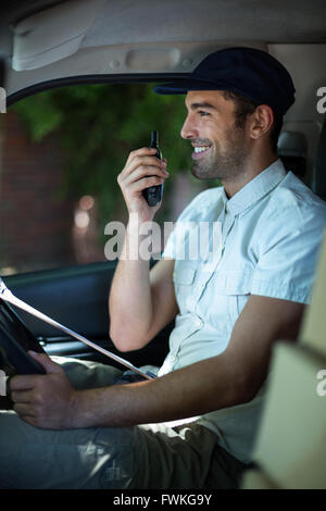 Smiling delivery man using walkie-talkie Stock Photo
