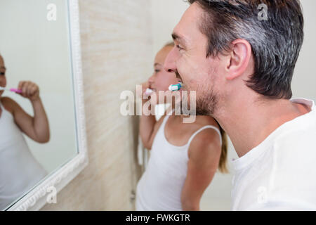 Father and daughter brushing their teeth in the bathroom Stock Photo