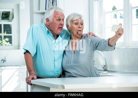 Senior couple making faces while taking selfie through phone Stock Photo