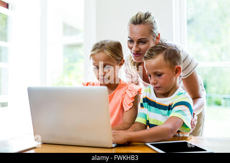 Mother teaching children to use laptop at home Stock Photo