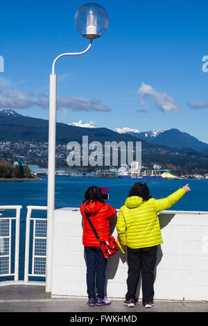 Two tourists in Vancouver looking across the harbour from Canada Place Stock Photo