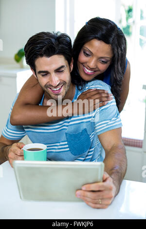 Young couple embracing while using digital tablet Stock Photo