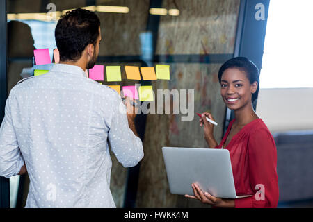Colleagues writing on sticky notes Stock Photo