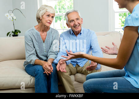Female consultant explaining senior couple at home Stock Photo